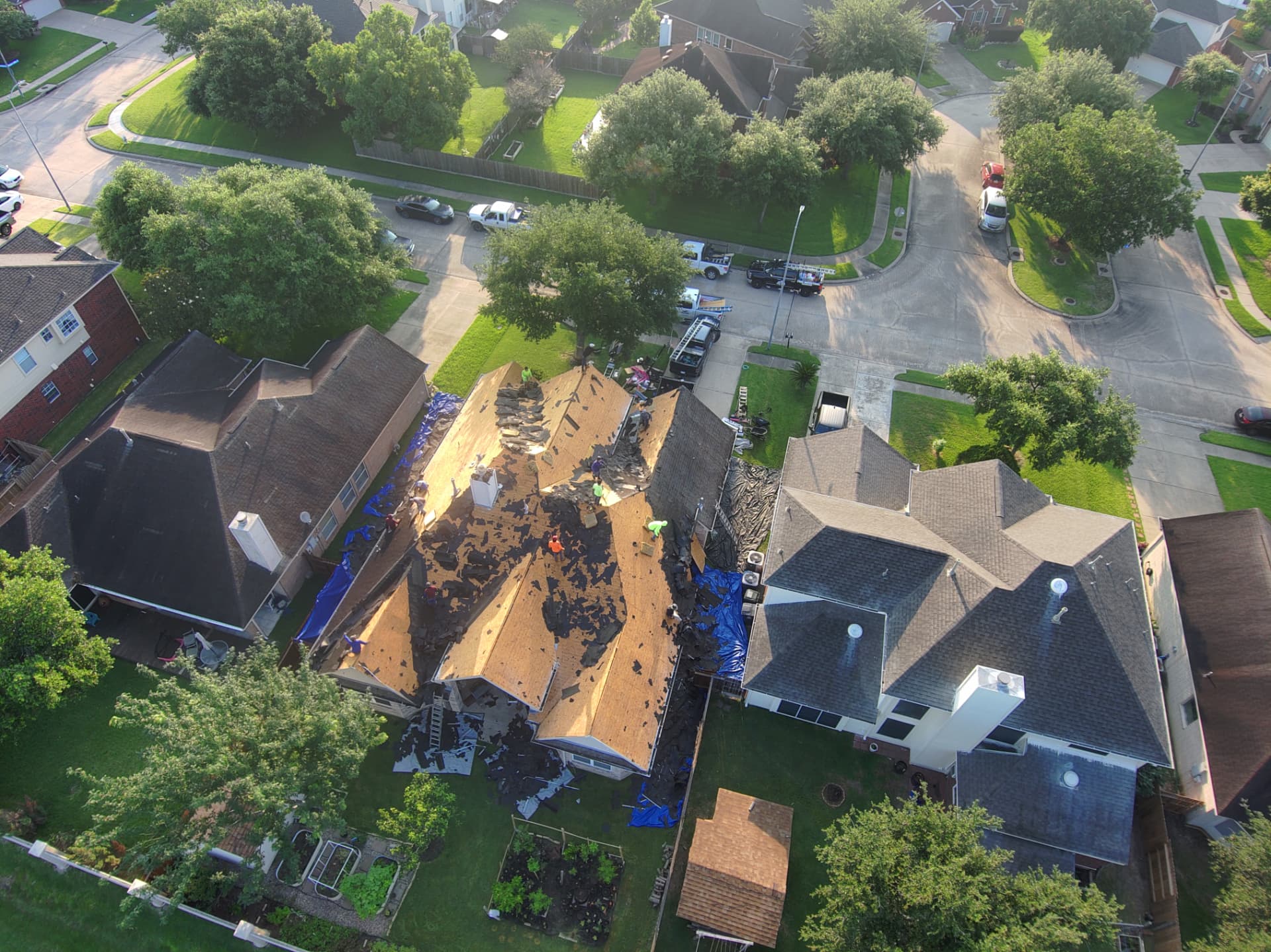 Aerial drone photo of a neighborhood roof replacement with decking exposed