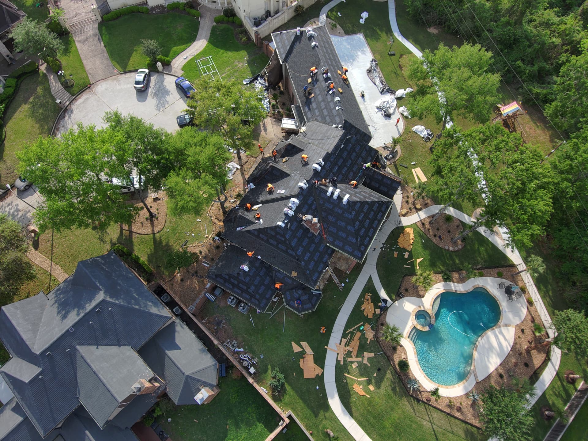 Drone photo of a large residential roof replacement with crew installing underlayment