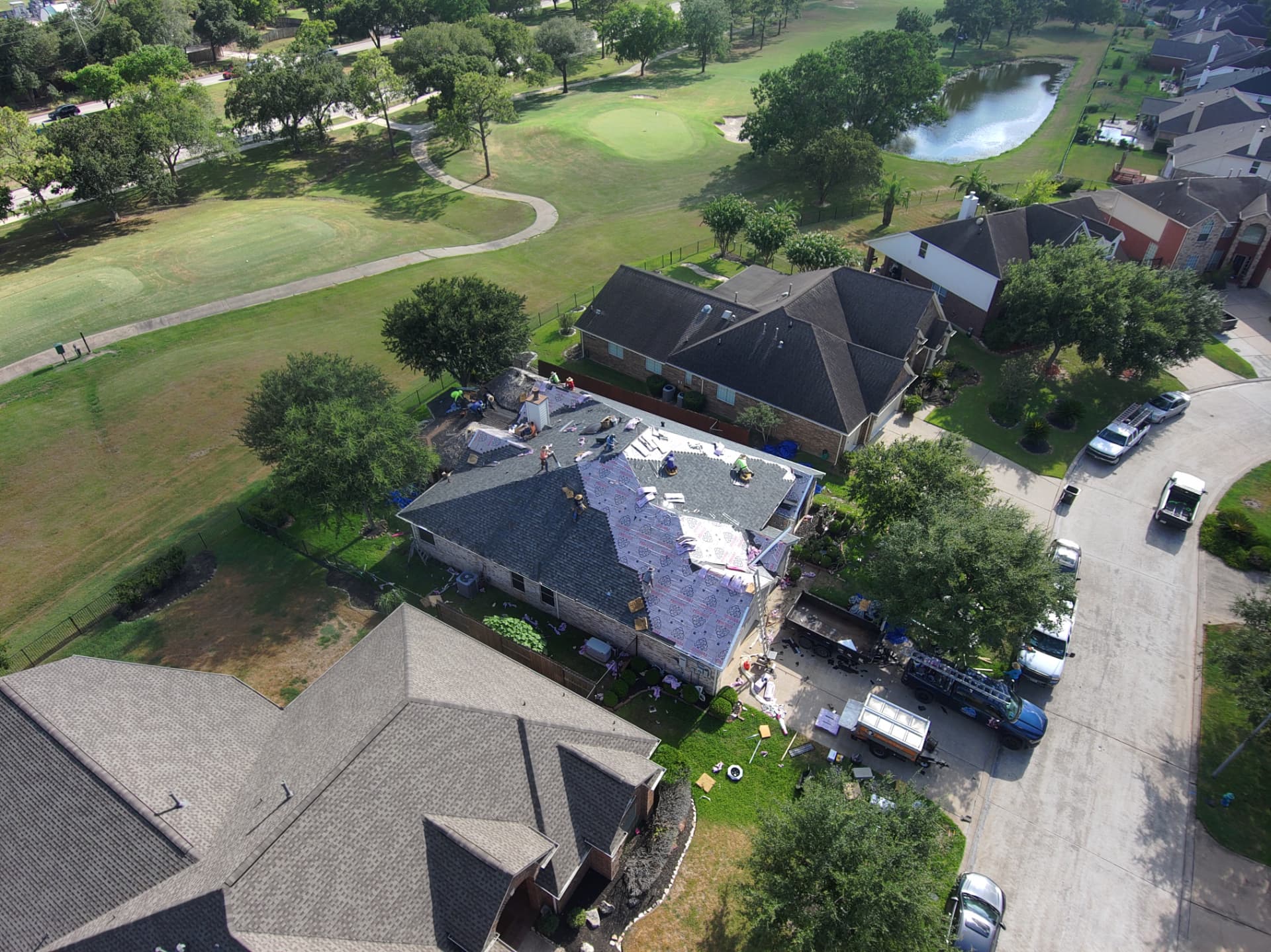 Aerial view of a roof tear-off down to decking with debris cleanup underway