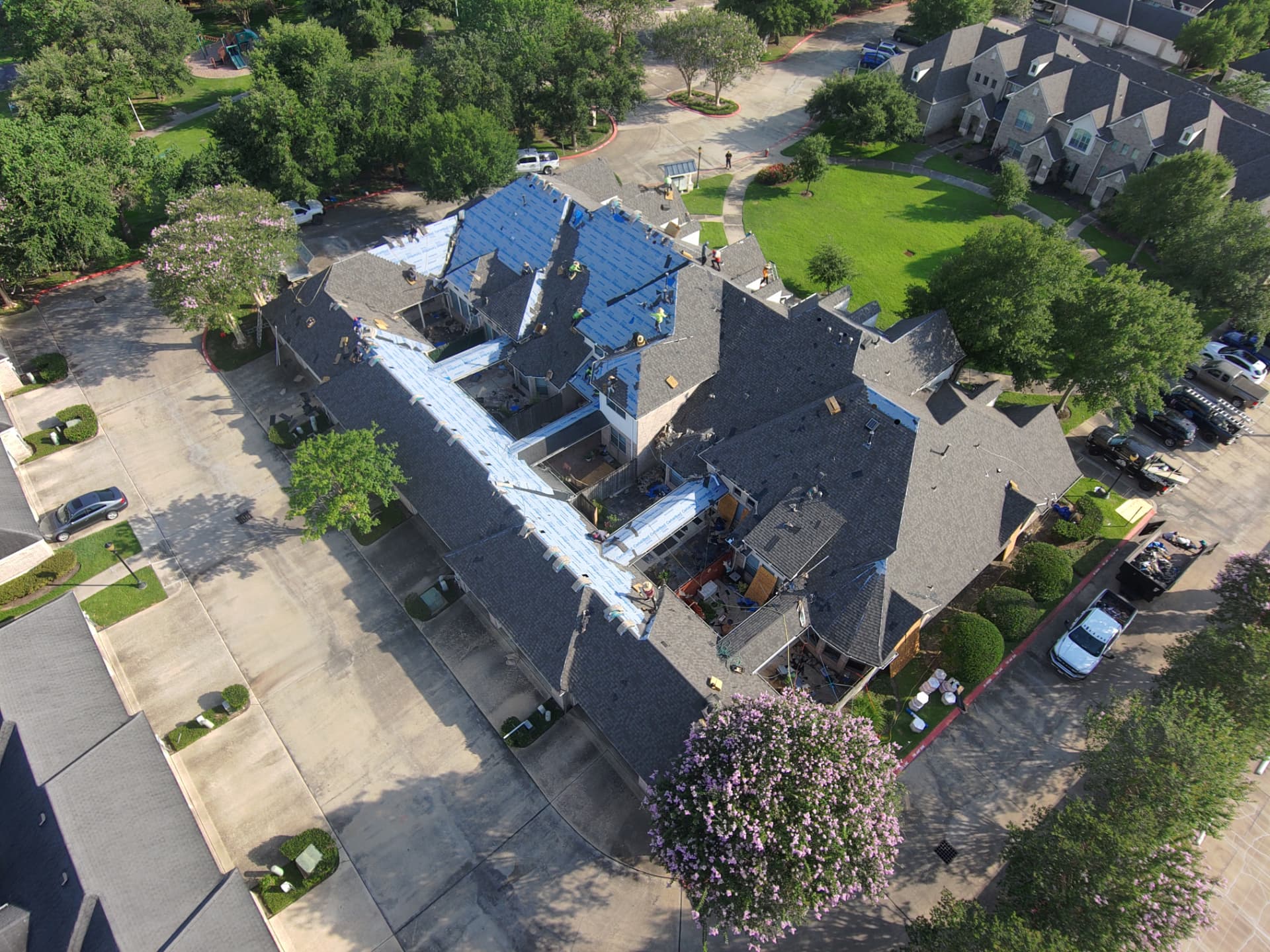 Drone photo of a multi-building roof replacement with crews working across sections